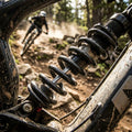 Graue Rockshox Feder für HR Dämpfer am dreckigen Mountainbike, während ein Fahrer auf staubigem Trail fährt.