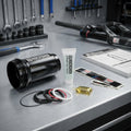RockShox Air Can und Service-Kit mit Dichtungen, Fett, Öl auf Werkbank für Deluxe/Super Deluxe Federgabeln.