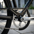 Schwarzer Horn Kettenschutz am Fahrrad-Antrieb mit silberner Kette und Kurbel.