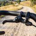 SHIMANO GRX Bremshebel BL-RX812 am Lenker eines Gravelbikes auf einem kurvigen Schotterweg.