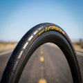 Continental Gatorskin Fahrradreifen 23-622 schwarz Draht auf Rad, mit gelbem Schriftzug und Straßenhintergrund.