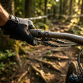 RockShox OneLoc Remote Upgrade Kit Hebel am Mountainbike-Lenker, Hand mit Handschuh, auf Waldweg.