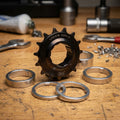 Single Speed Ritzel (17 Zähne) und Distanzring-Set auf Holz-Werkbank mit Werkzeug.