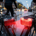Herrmans Gepäckträgerrücklicht H-Trace Dynamo 50mm StVZO leuchtet rot an Fahrrädern auf nasser Straße.
