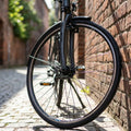 Exal VR ZX19 28 Vorderrad für Felgenbremse, robust, am Fahrrad auf Kopfsteinpflaster an Ziegelwand gelehnt.