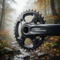 Schwarzes SHIMANO DEORE 32 Zähne Kettenblatt und Kurbel für langlebigen MTB-Antrieb, abgebildet auf einem Waldweg.