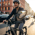 Lachender Mann auf E-Bike mit Busch&Müller Cycle Star E Fahrradspiegel, der den Stadtverkehr hinter ihm reflektiert.