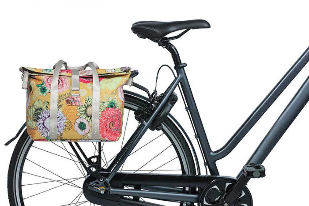 Basil Bloom Field Schultertasche honiggelb mit Blumenmuster am Fahrrad-Gepäckträger befestigt.