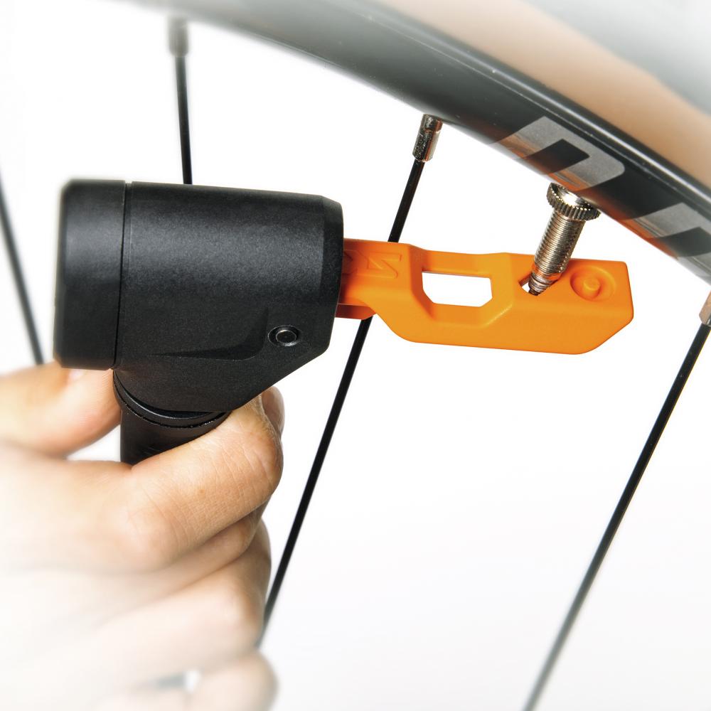SKS MV EASY Pumpenkopf mit orangefarbenem Adapter an Presta-Fahrradventil auf einem Reifen.
