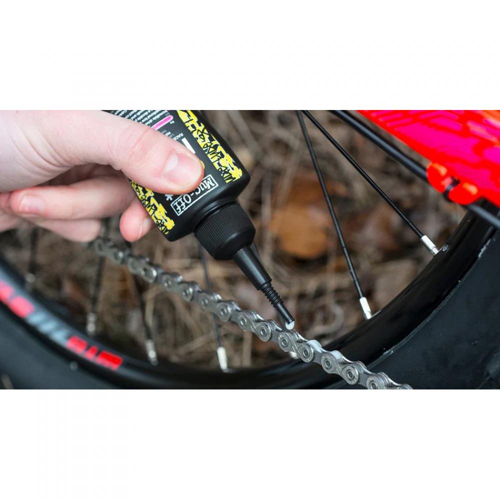 Hand trägt wachsbasierte Muc-Off Dry Lube Kettenschmiermittel auf Fahrradkette auf, für trockene Bedingungen.