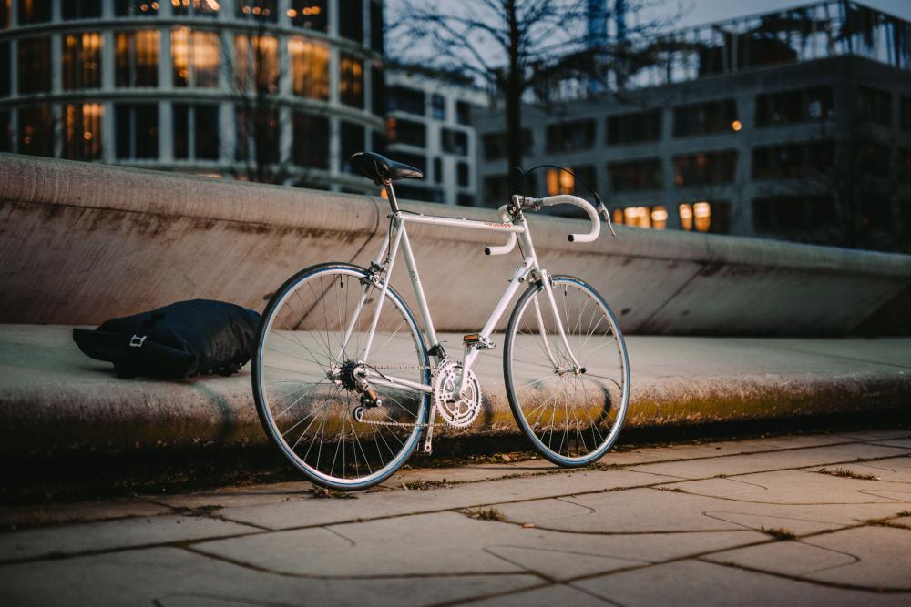 Weißes Rennrad mit Continental Ultra Sport III 28-622 Faltreifen vor Betonbank in der Stadt bei Dämmerung.