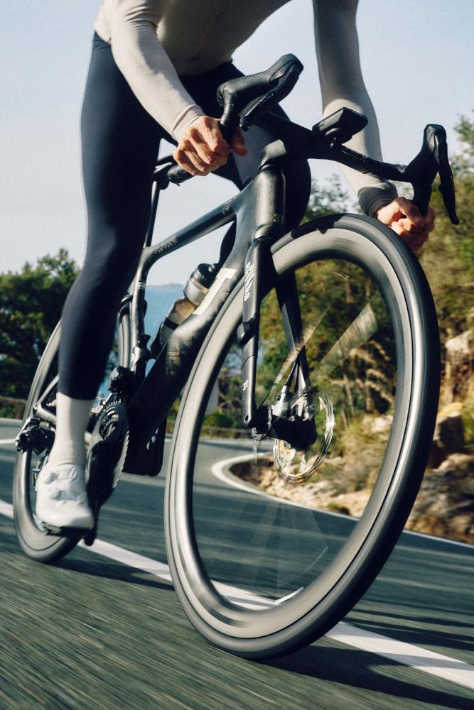 Rennrad mit schwarzen Continental Grand Prix 5000 S TR Tubeless-Ready Reifen fährt schnell auf kurviger Straße.