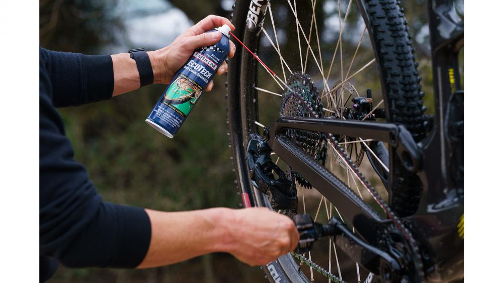 Finish Line EcoTech biologisch abbaubarer Fahrradreiniger wird auf eine schmutzige Fahrradkette gesprüht.