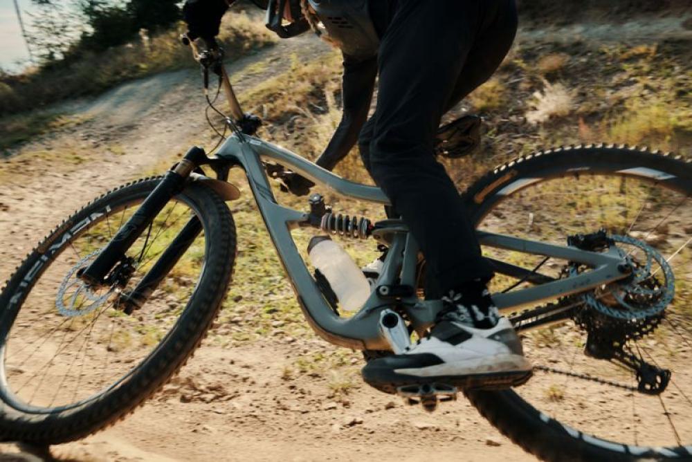 Mountainbike mit FIDLOCK TWIST 750ml Compact Trinkflasche und magnetischem Halter auf dem Trail.