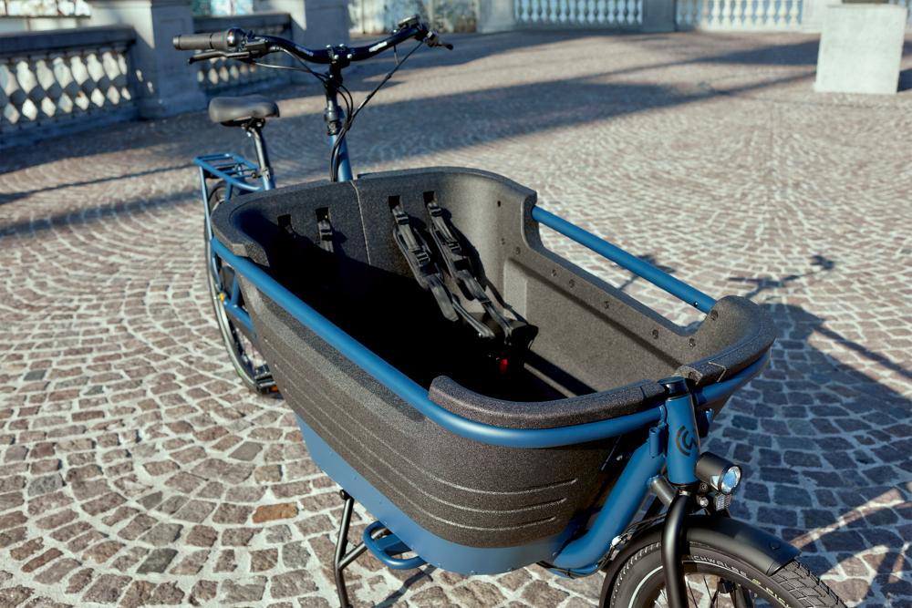 Lepper Zusätzliche Sitzbank SC3 in Lastenfahrrad-Frontbox mit Gurten auf sonnigem Kopfsteinpflaster