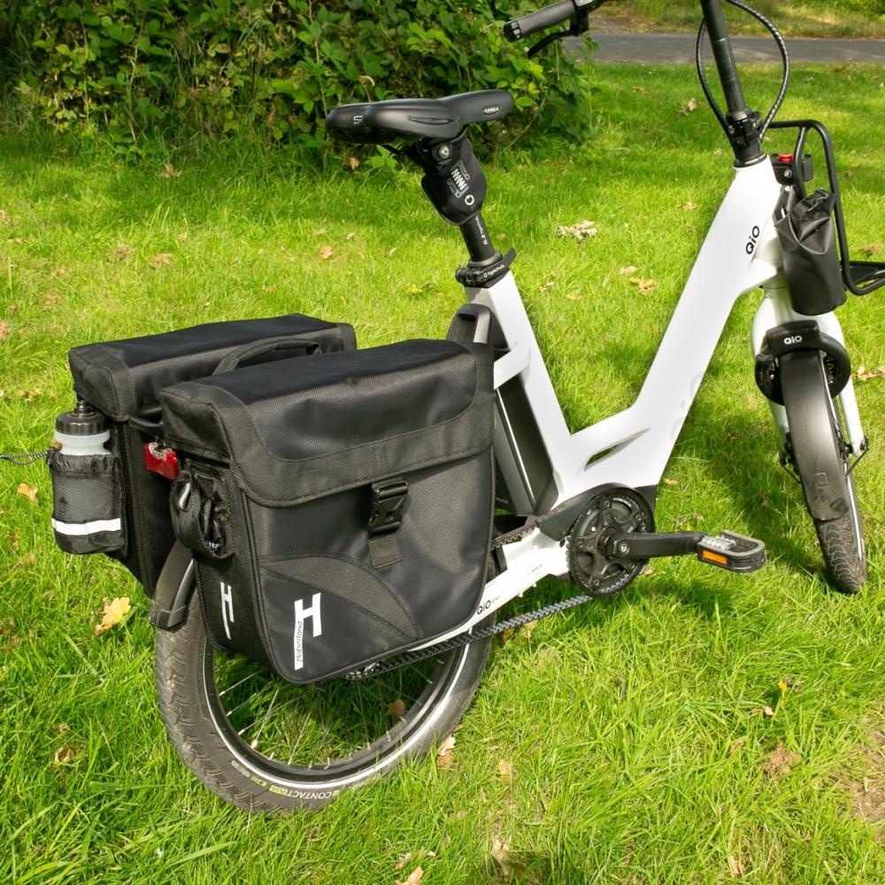 Geräumige schwarze Haberland Doppeltasche 31l Carry On an weißem E-Bike im Grünen für Alltag und Tour.