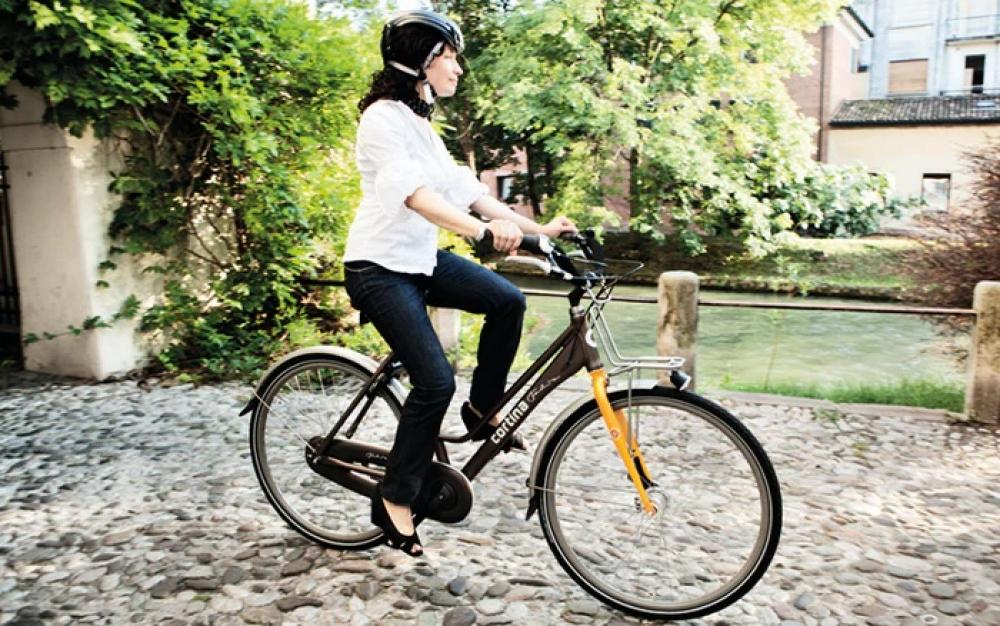 Frau fährt aufrecht und entspannt Fahrrad auf Kopfsteinpflaster, ideal für komfortablen Fahrradsattel mit aufrechter Sitzposi