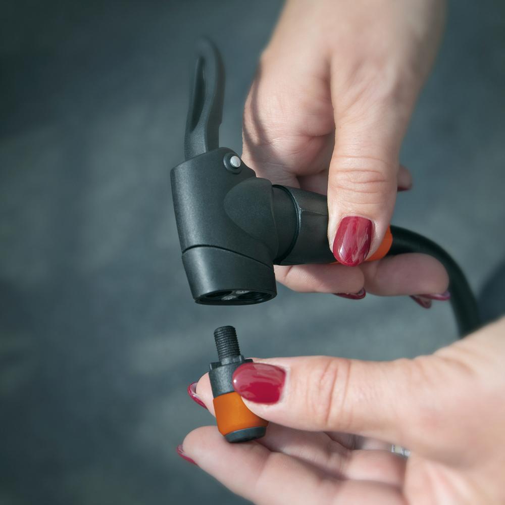 Frau hält SKS Clik-Valve Adapter und Pumpenkopf für einfachen Ventilwechsel. Kompatibel mit SKS-Pumpen, präzise und sicher.