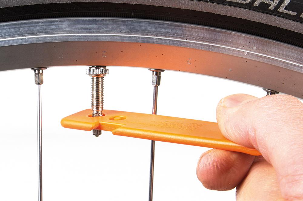 SKS Reifenheber orange aus robustem Kunststoff im Einsatz am Fahrradventil für einen schnellen Reifenwechsel.