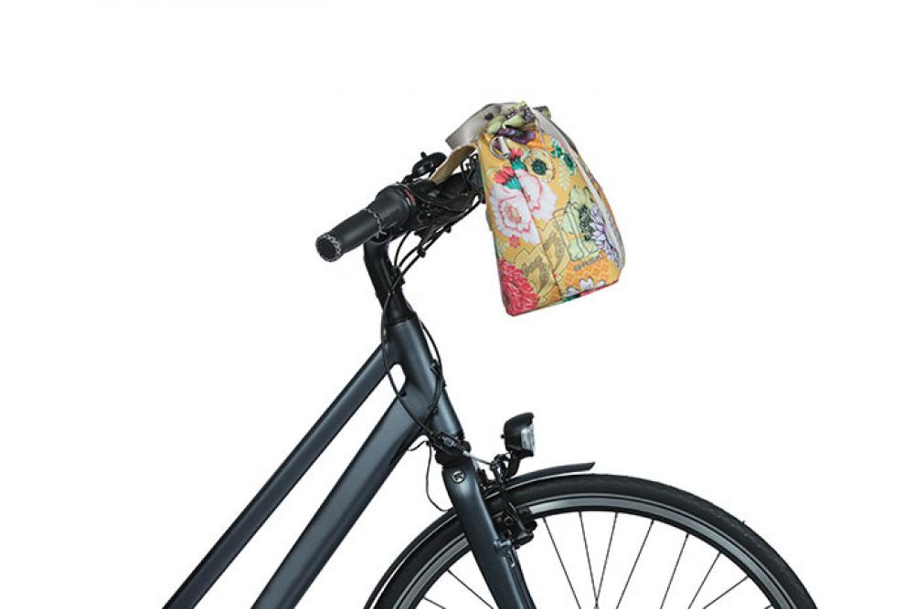Fahrrad mit Basil Bloom Field Schultertasche honiggelb am Lenker befestigt.