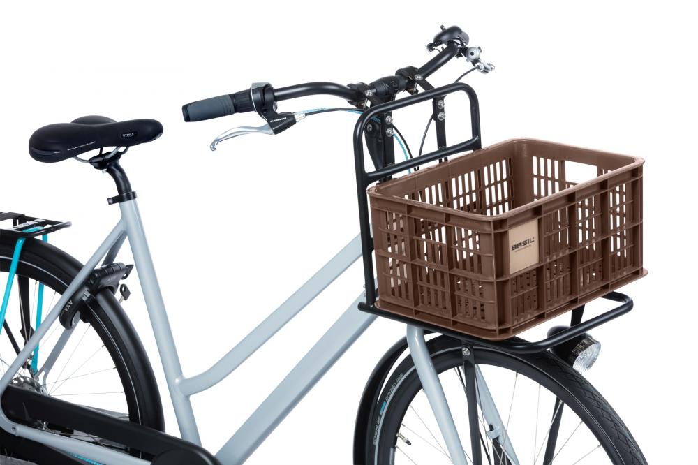 Braune BASIL Crate S Fahrradkiste aus recyceltem Kunststoff (17,5L) auf dem Frontträger eines hellgrauen Fahrrads.