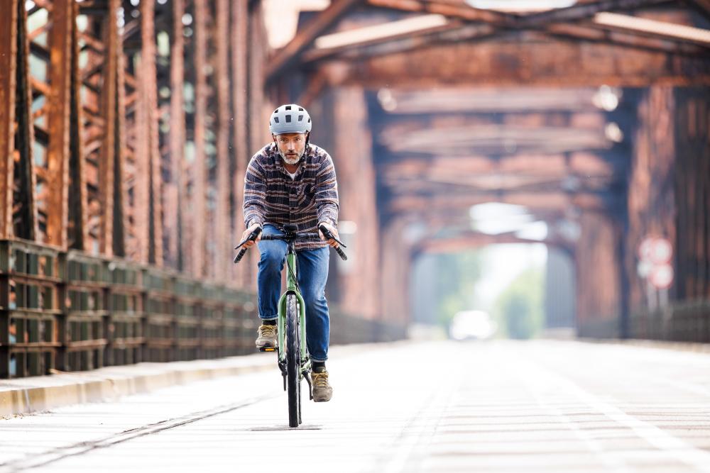 Schwalbe Marathon Efficiency Evo V-Guard Super Race 45-622 Touren-Faltreifen schwarz am Fahrrad, Mann fährt auf Brücke.