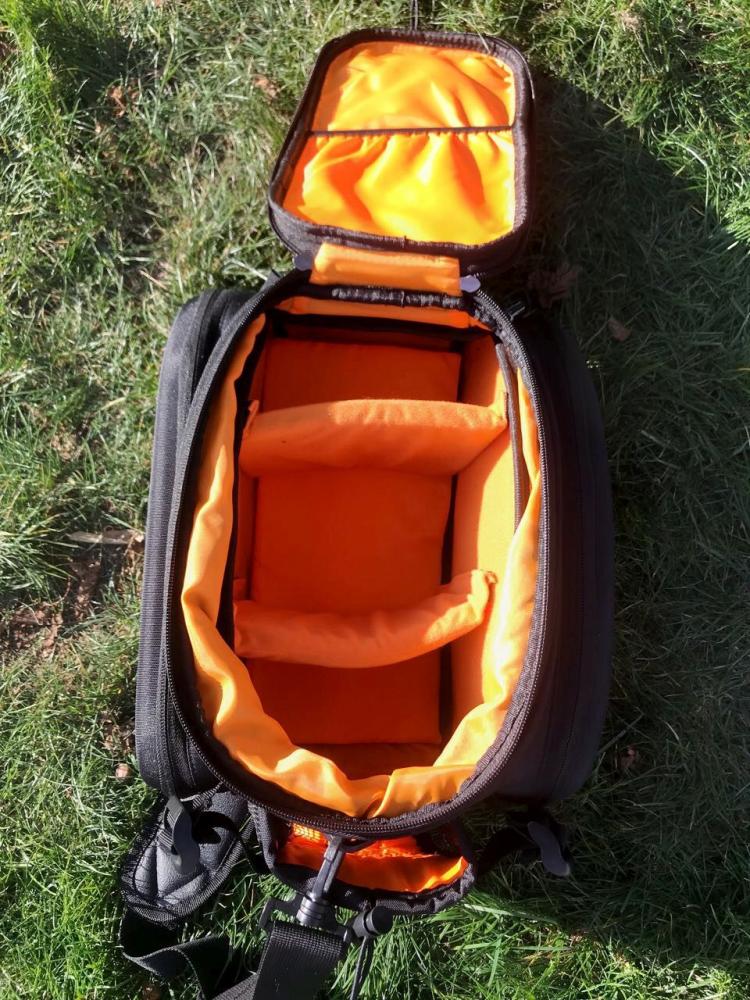 Greendonkey Gepäckträgertasche Hermann RT schwarz, offen mit orangefarbenen, gepolsterten Fächern auf Gras.