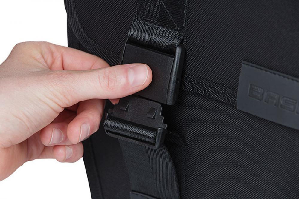 Hand öffnet schwarze Schnalle an Basil Fahrradtasche Tour Single schwarz, 14l, wasserabweisend.