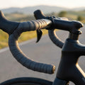 Deda Lenkerband anthrazit mit Stopfen am Rennrad, Detailaufnahme bei Sonnenlicht.