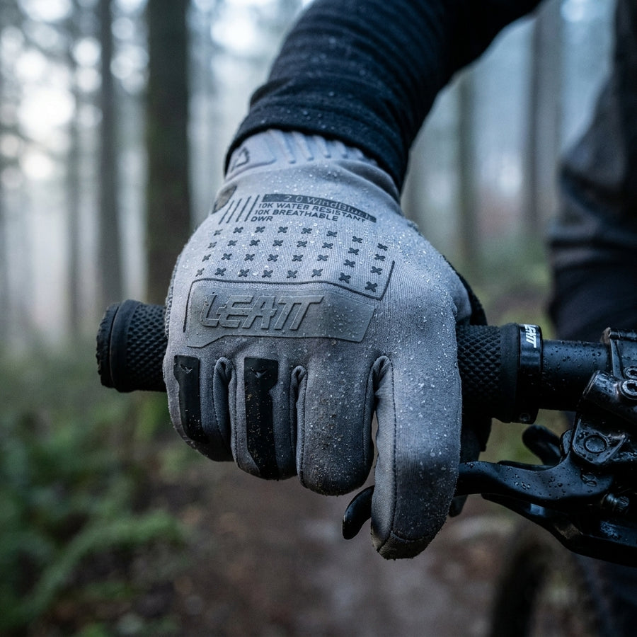 Leatt Glove MTB 2.0 WindBlock Fahrradhandschuhe Titanium, winddicht, wasserabweisend, mit Wassertropfen am Lenker im Wald.