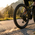 Schwalbe MARATHON PLUS MTB Reifen auf Mountainbike, das bei Sonnenuntergang Staub auf Schotterweg aufwirbelt.