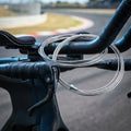 Aufgerollter SRAM Edelstahl Bremszug für Triathlon-Lenker auf Fahrrad vor Rennstrecke.