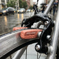 Kool-Stop V-Brake City Bremsschuhe lachsfarben am nassen Fahrrad bei Regen auf der Straße.