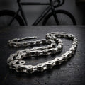 Silberne Miche Pista Fahrradkette 1/2x1/8 Zoll, 114 Glieder, auf dunklem Holztisch mit Fahrrad im Hintergrund.