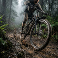 Mountainbiker fährt durch schlammigen Waldweg, X-CAPE VR-Schutzblech schützt effektiv vor Spritzwasser.