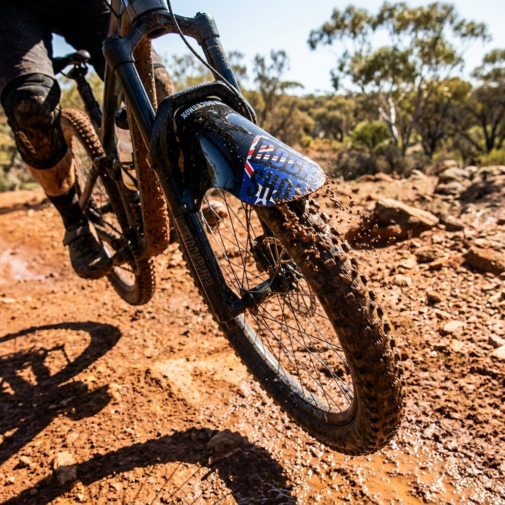 Rockshox Fender vorne am Mountainbike mit Australien-Flagge im Schlamm, spritzt Dreck beim Fahren.
