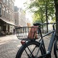 Basil Hinterrad-Korb PORTLAND Aluminium matt schwarz am Fahrrad mit Baguette und Notizbuch in der Stadt.