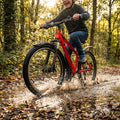 GRT.SCHUTZBLECHE POLISPOR T EXPANDER 65 26/29" an rotem Fahrrad, das durch eine Pfütze spritzt.