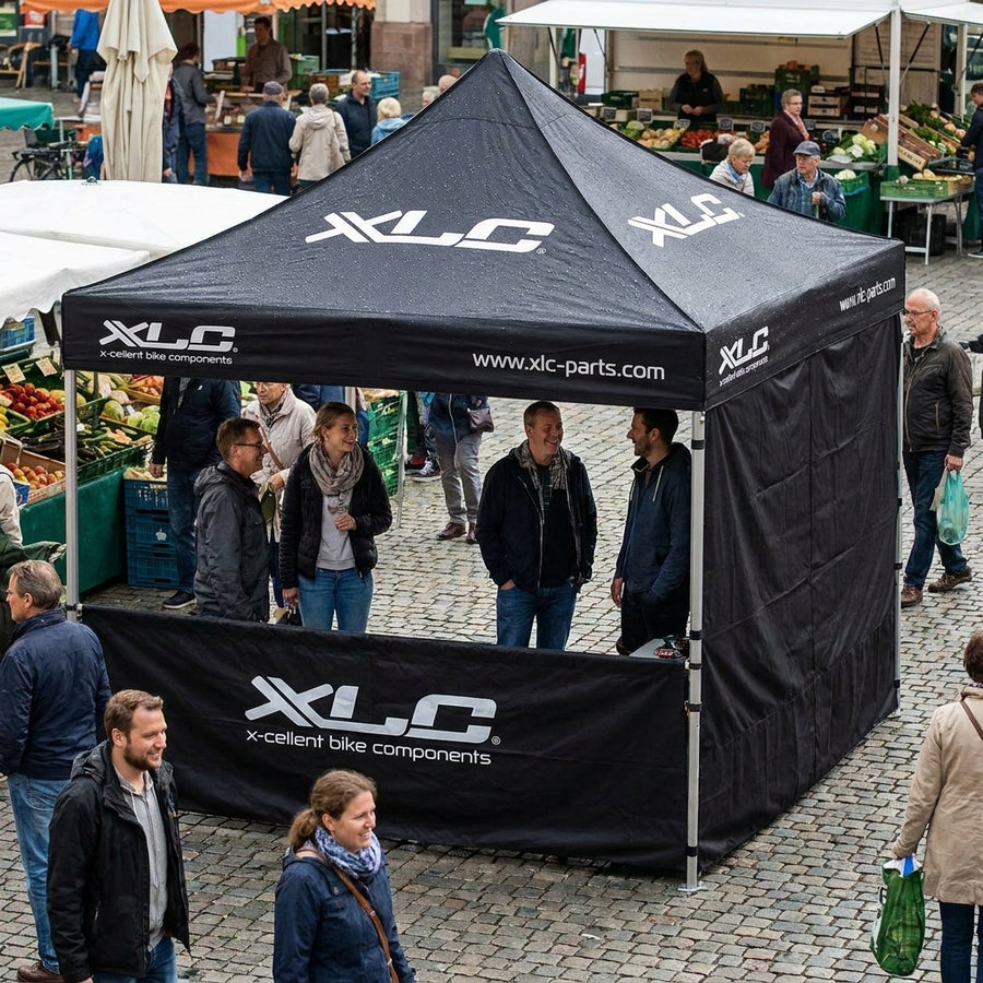 XLC schwarzes 3x3m Faltzelt mit Seitenwand und Logo auf belebtem Marktplatz.