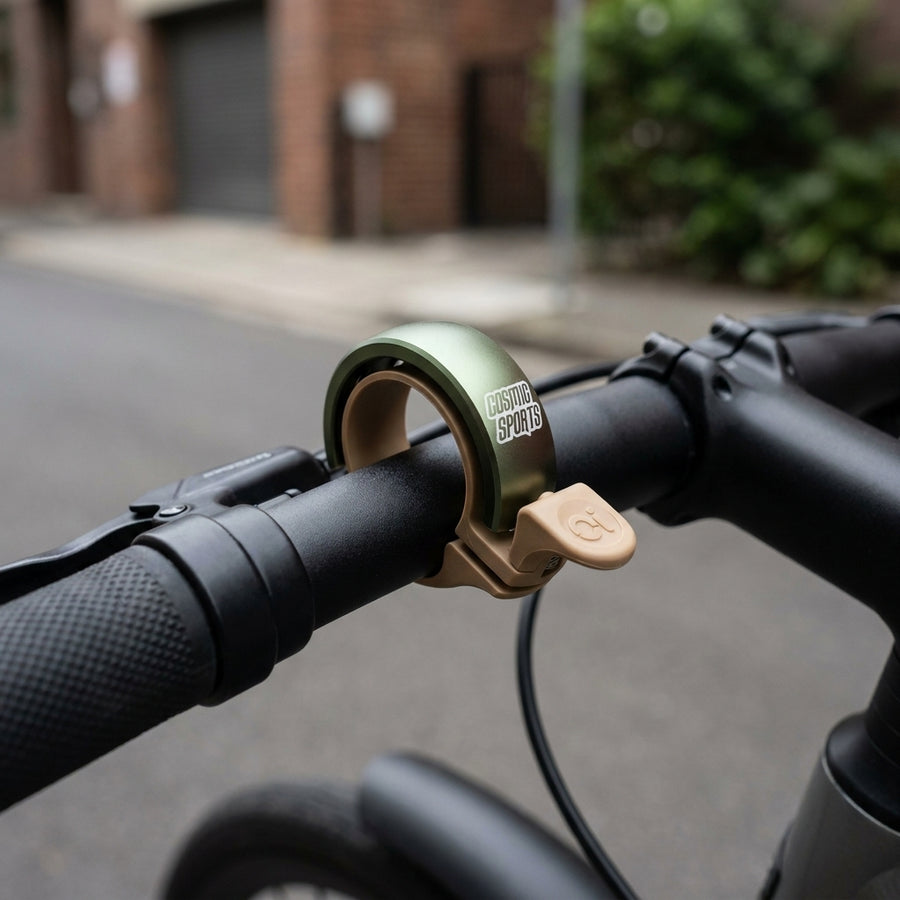Knog Oi Classic Fahrradklingel, grün-sandbraun matt, am Lenker. Groß 23.8-31.8mm.