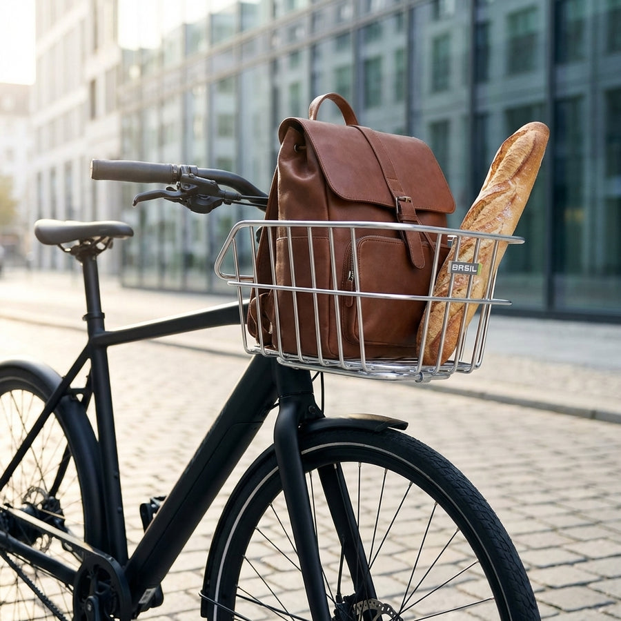 Alufarbener Basil Cento Aluminium Fahrradkorb mit braunem Lederrucksack und Baguette auf schwarzem Rad.