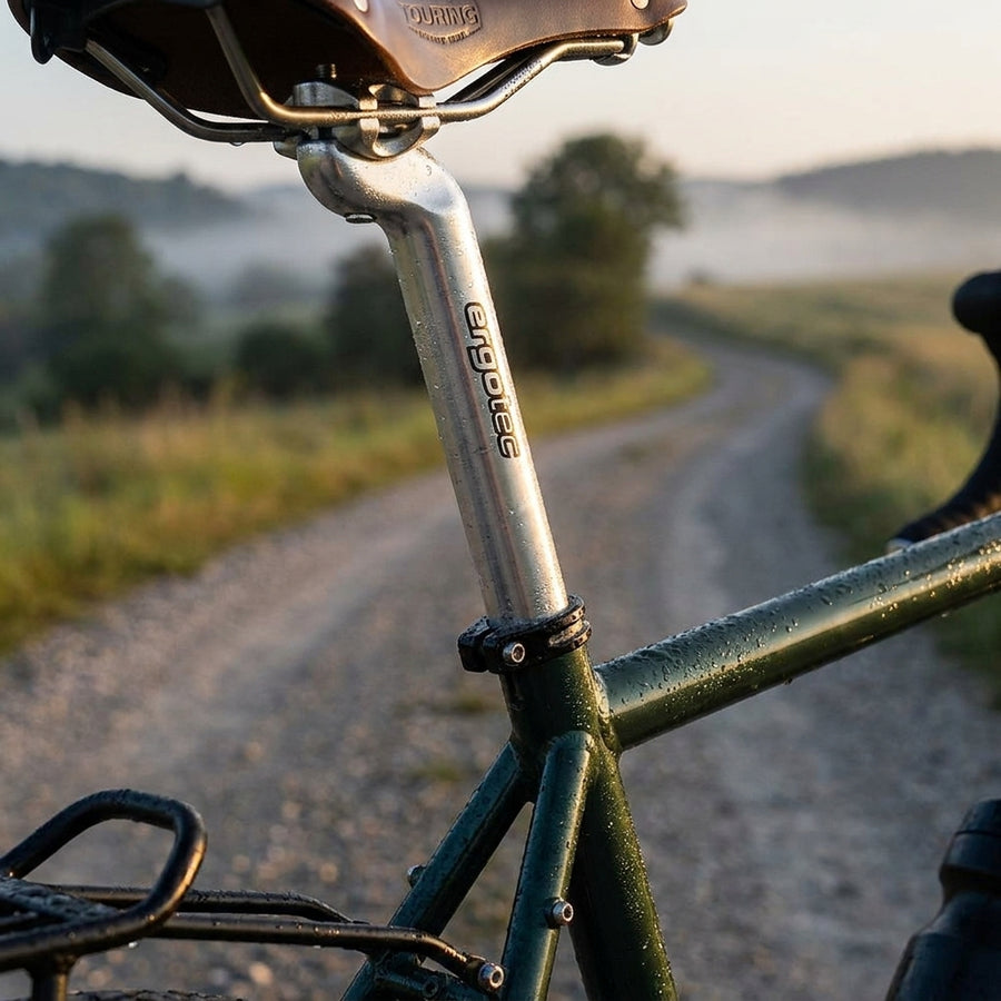 Ergotec Patentsattelstütze silber am Fahrrad mit Tautropfen, auf einem Gravelweg im Morgennebel.