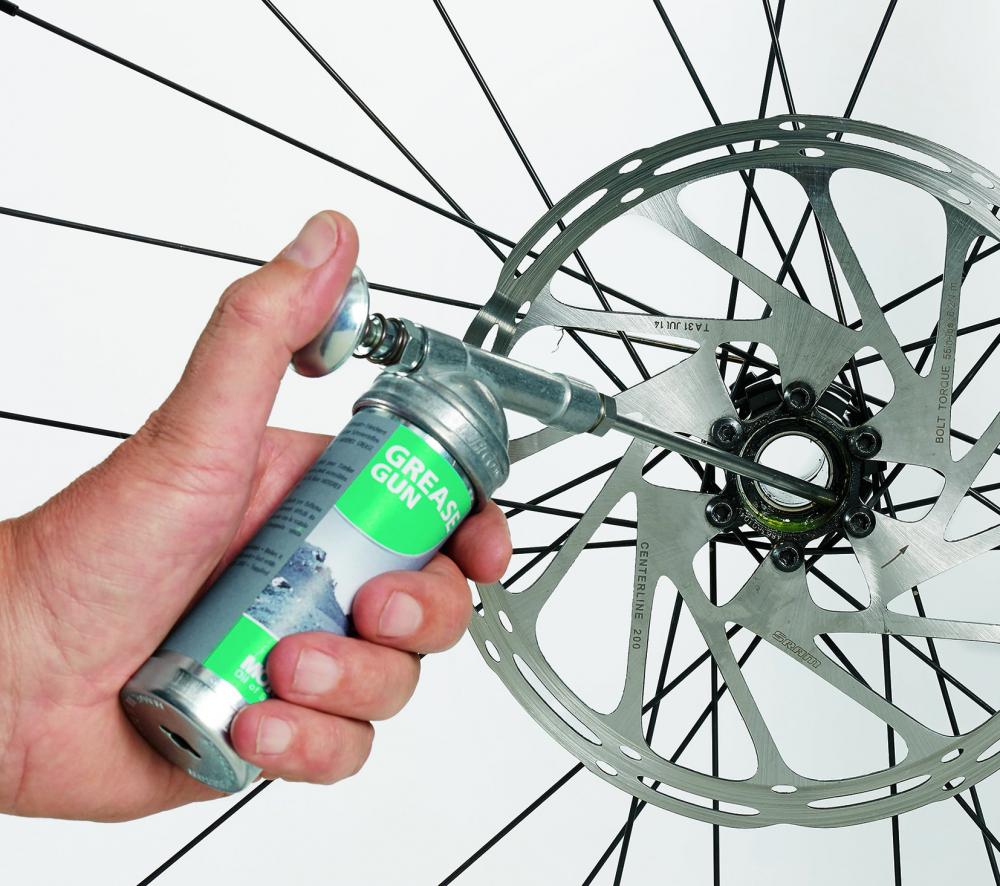 Hand fettet präzise eine Fahrradnabe mit der MOTOREX Fettpresse BIKE GREASE GUN.