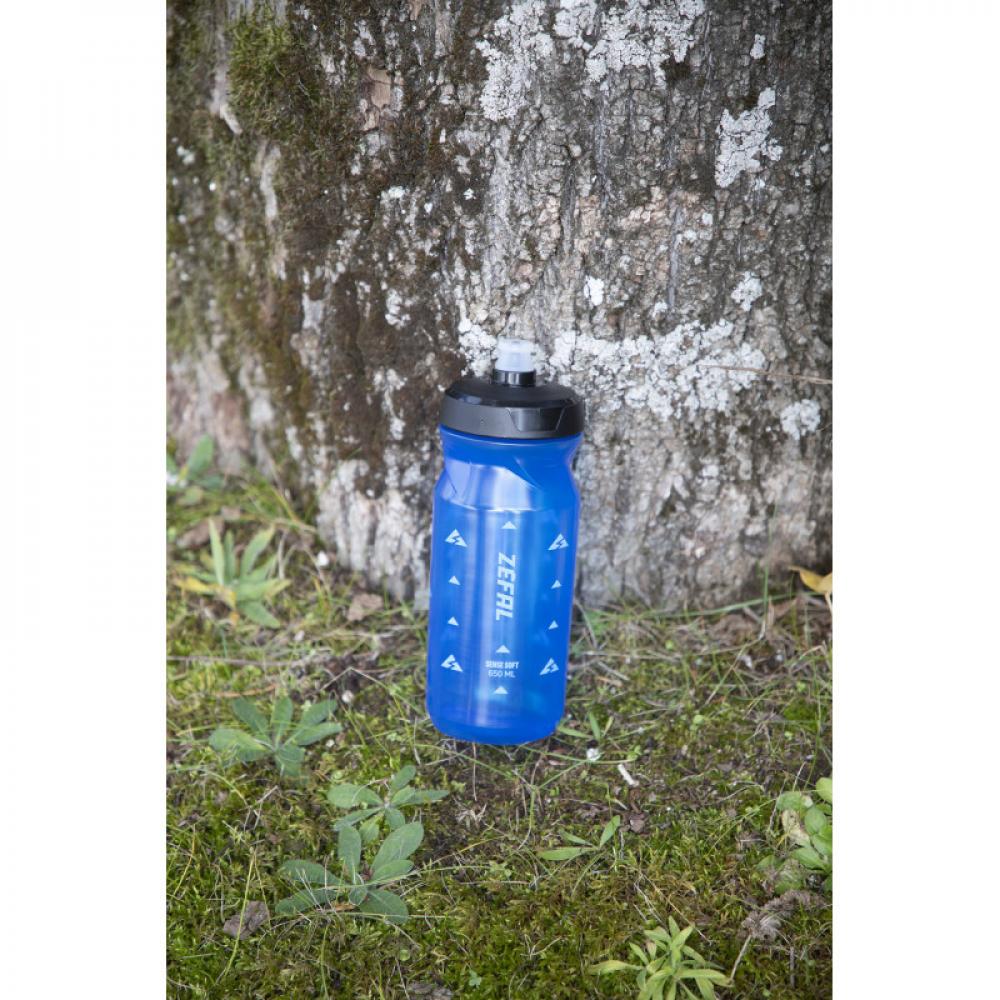 Zefal Trinkflasche Sense Soft 65, 650ml in transluzent Blau vor einem Baumstamm auf einer Wiese.