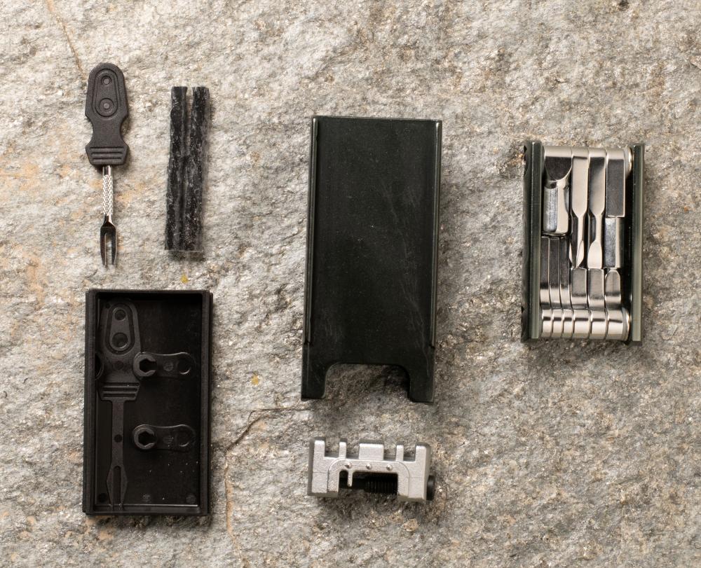 Crankbrothers F16 Multitool schwarz silber mit Reifen- und Kettenwerkzeug, zerlegt auf Stein.