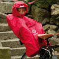 Kind im roten Hamax Regenponcho in Fahrradsitz, geschützt vor Regen.