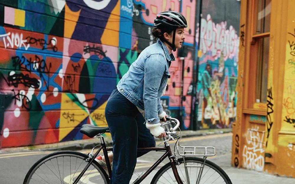 Radfahrerin auf Fahrrad mit schwarzem Selle Royal Ellipse Premium Sattel vor bunter Graffiti-Wand.