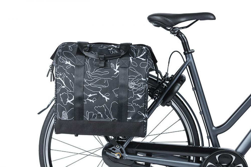 Schwarze Basil Grand Flower Shoppertasche mit floralem Muster und Hook On-System am Fahrrad-Gepäckträger.