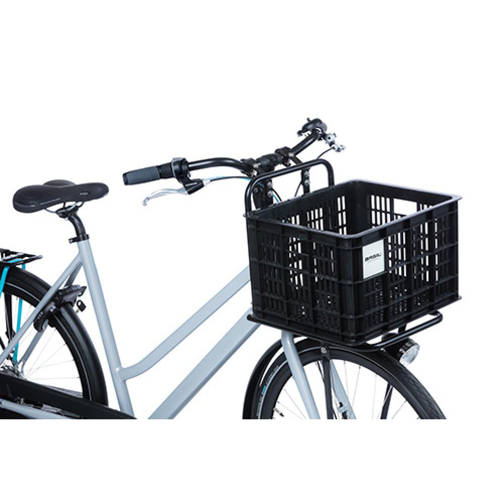 Schwarze Basil Crate M Fahrradkiste 29,5L auf dem Frontgepäckträger eines grauen Fahrrads montiert.