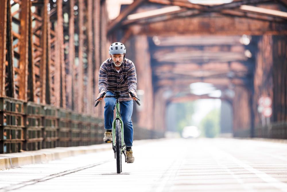 Mann radelt auf Schwalbe Marathon Efficiency Evo V-Guard Schwarz Reflex Tourenreifen 35-622 auf Brücke.